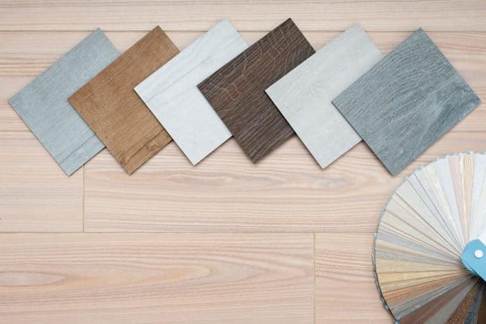 An example of a catalog of luxury vinyl laminate floor tiles and a designer palette with textures with a new interior design for a house or floor on a light wooden backgr